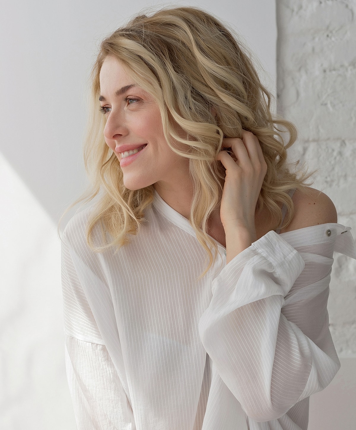 Smiling woman with wavy blonde hair in daylight.
