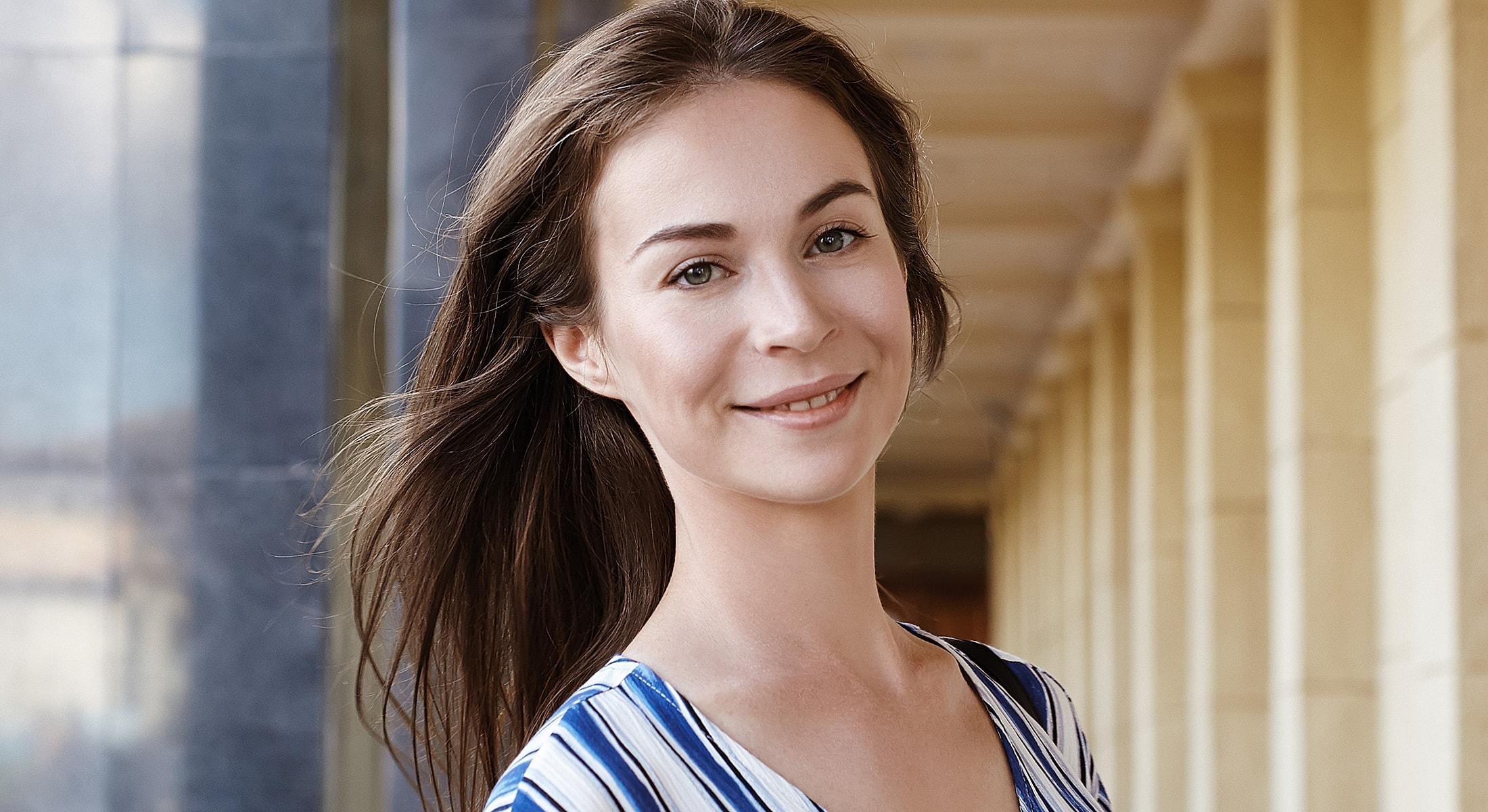 Smiling woman in striped shirt outdoors.