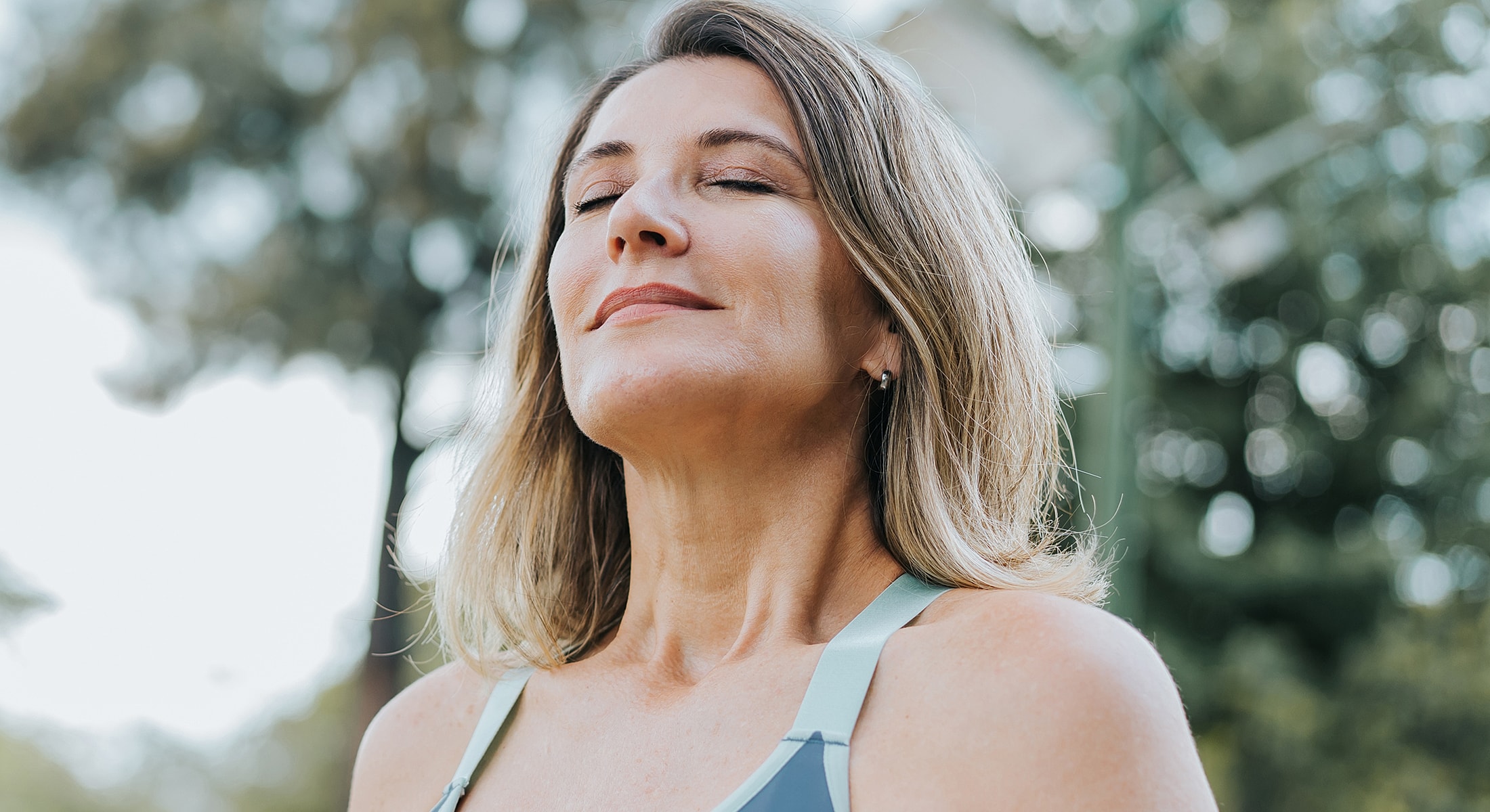 Woman enjoying tranquility outdoors, eyes closed.